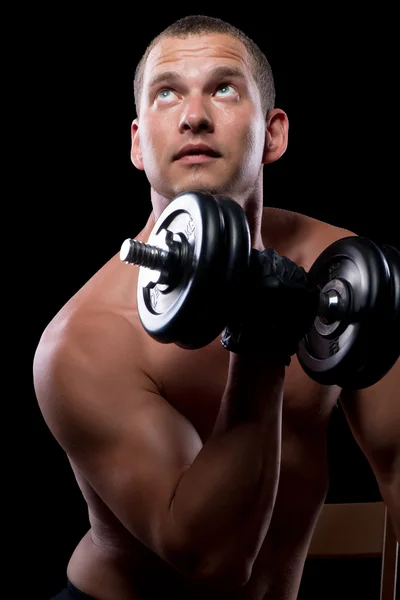 Pensive bodybuilder while training with dumbbells