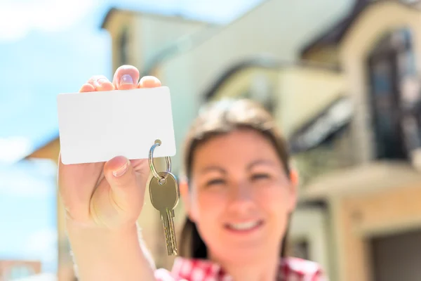 Card with a key in hand of happy woman. focus on the key