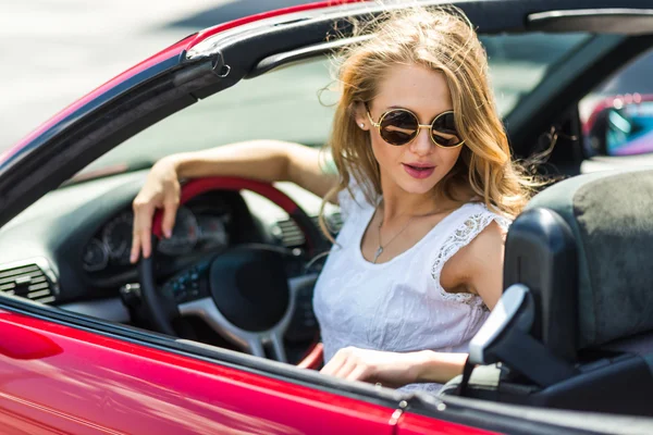 Beautiful blonde girl in a red convertible car