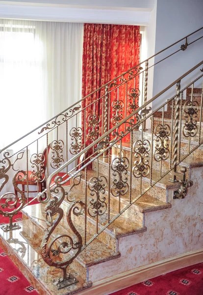 Marble stairs with golden metal handle leading up. Luxurious stairs with red curtains on background