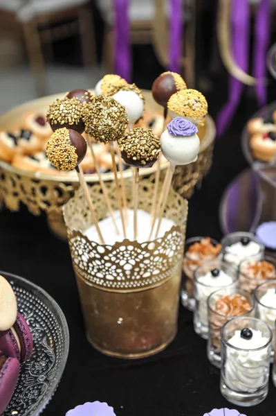Wedding decoration with various lollipops in golden support, cupcakes, meringues, muffins and macaroons. Elegant and luxurious event arrangement with different types of desserts. Wedding dessert