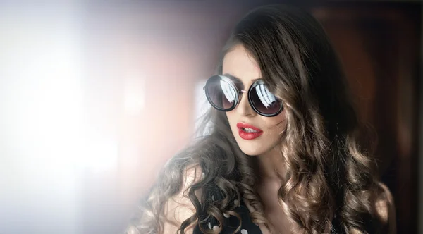 Woman with black sunglasses  and long curly hair. Beautiful woman portrait. Fashion art photo of young model with sunglasses. Elegant female portrait isolated. Romantic. Beauty. Modern style