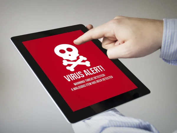 Hands with tablet with virus alert on the screen