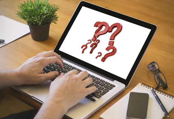 Man working on laptop with question marks on the screen