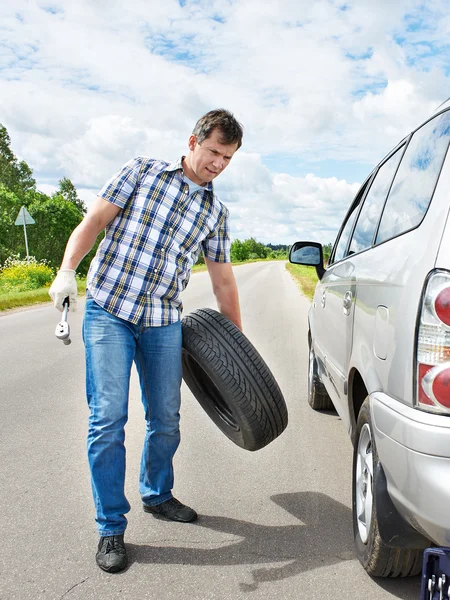 Man changing a spare tire of car