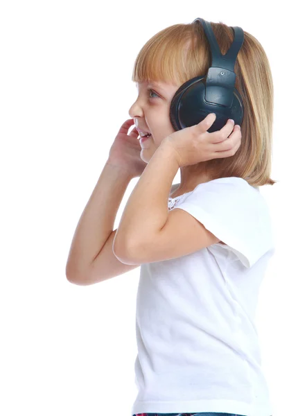 Girl listening to music with big black headphones standing sidew