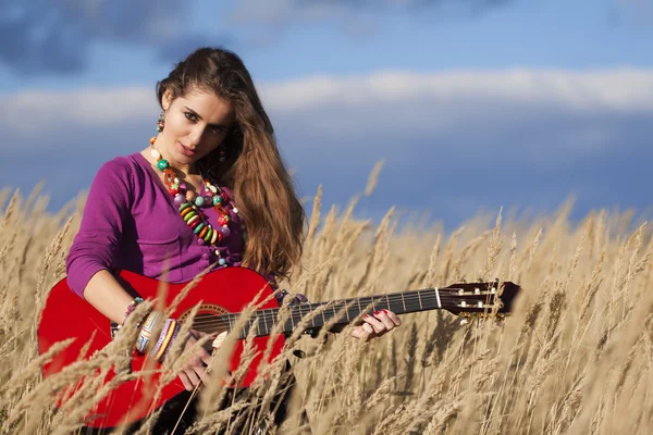 Young country woman playing guitar in field
