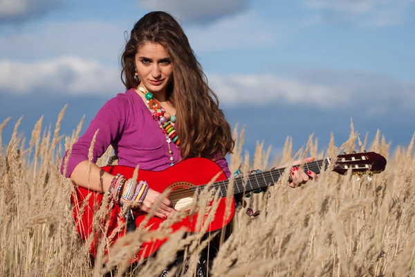 Young country woman playing a guitar in field