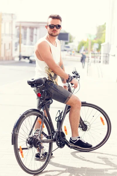 Young hipster man with bike in the city in sunny summer day