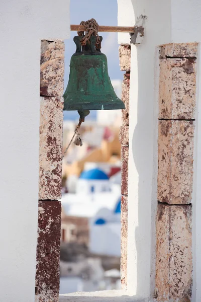 Church bell against churches in Oia village on Santorini island, Greece