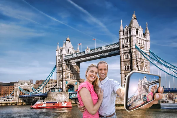 Tourist couple taking selfie against Tower Bridge in London, England, UK