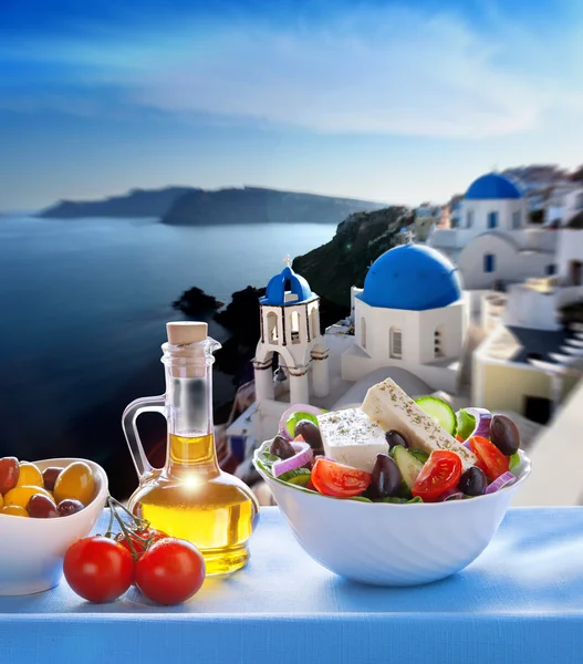 Greek salad against church in Oia village, Santorini island in Greece