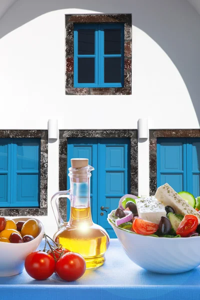 Greek salad against old greek house, Santorini island, Greece