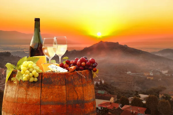 White wine with barrel against colorful sunset in Chianti, Tuscany, Italy