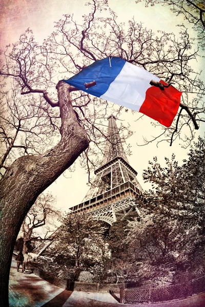 Eiffel Tower with French flag flying on the tree in France