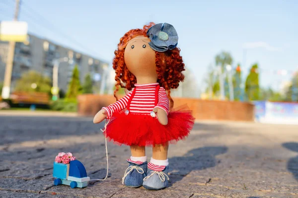 Red-haired handmade doll with a toy car