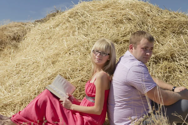 Young couple in love in the open field are sitting back to back