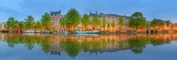 Panoramic view and cityscape of Amsterdam with boats, old buildings and Amstel river, Holland, Netherlands