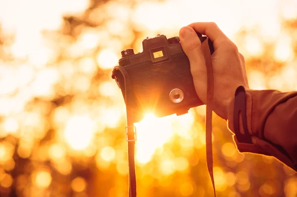 Man hand holding retro photo camera outdoor hipster Lifestyle with sun lights bokeh
