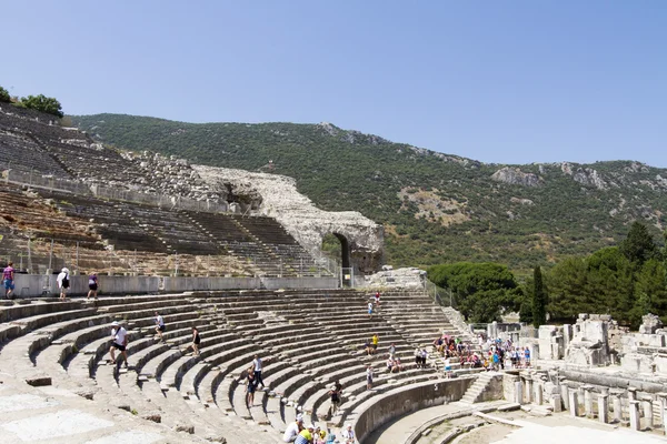 Tourists on the benches and the stage of the ancient theater in Ephesus