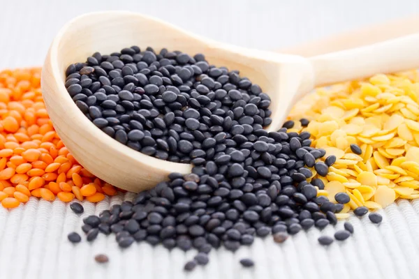 Wooden spoons with black, red and yellow lentils