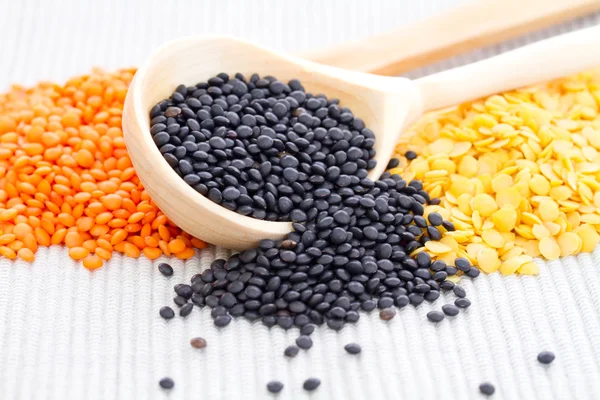 Wooden spoons with black, red and yellow lentils