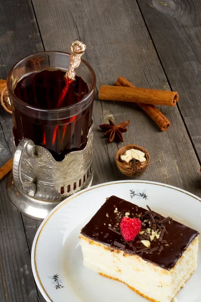 Cake with chocolate cream and a cup of tea in the cup holder of