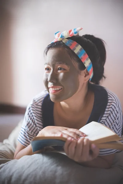 Woman doing mud facial masking at home spa