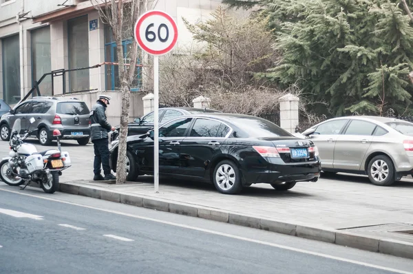 Dalian police officer writing parking ticket.