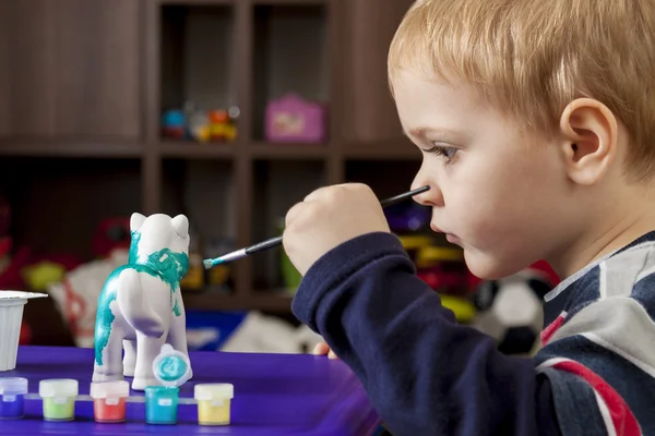 Boy painting ceramic figure