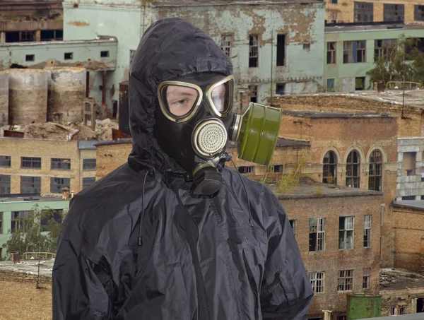 Person in gas mask against the backdrop of abandoned production