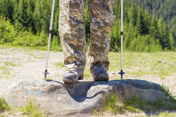 Hiker legs in hiking boots and part of trekking poles