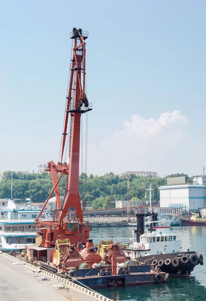 Floating crane and marine tug at the sea port berth