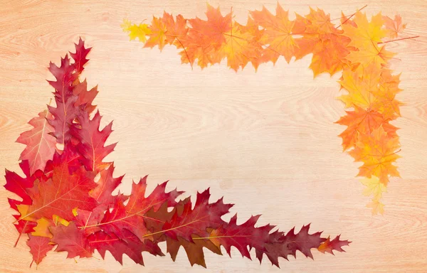 Frame of autumn leaves on a wooden surface