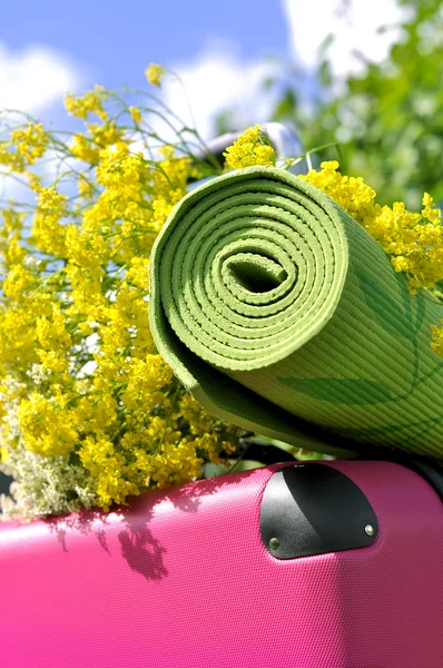 Suitcase with flowers and yoga mat