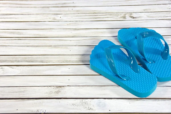 Turquoise flip-flops on wooden deck