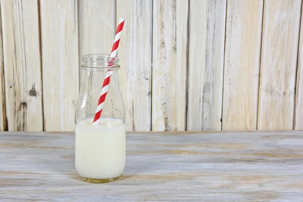 Retro milk bottle with white milk and striped straw