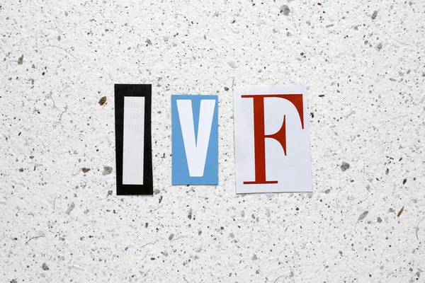 IVF (In Vitro Fertilization) acronym cut from newspaper white handmade paper texture