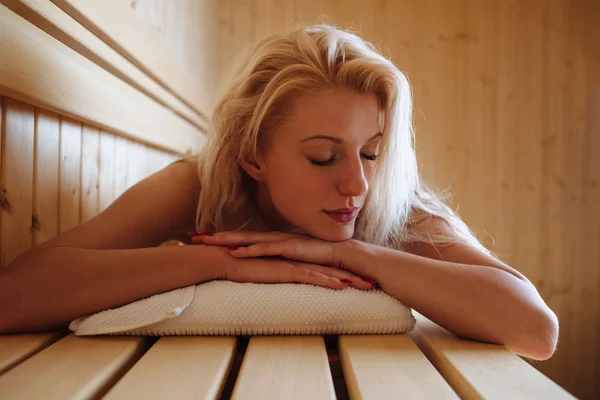 Woman lying relaxed in wooden sauna