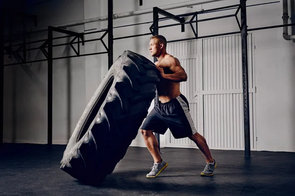 Athlete flipping tire at gym