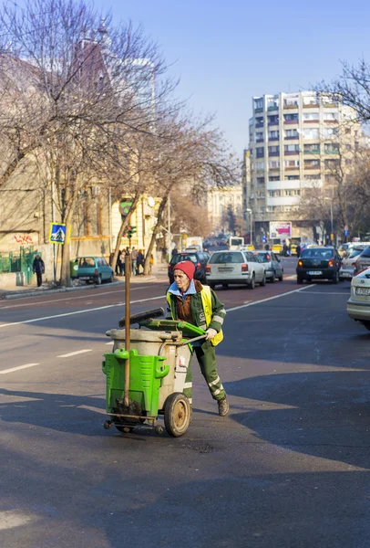 Woman street worker pushing a cleaning trolley