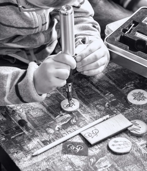 Children hands drawing a bicycle with a solid-point burner