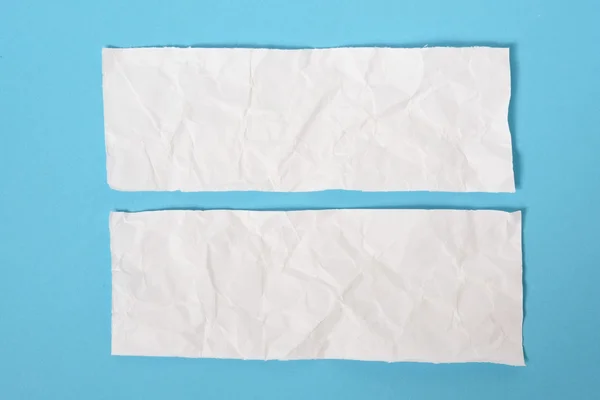 White ripped pieces of news paper on on blue background.