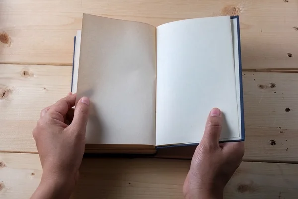 Hands hold book on wood table
