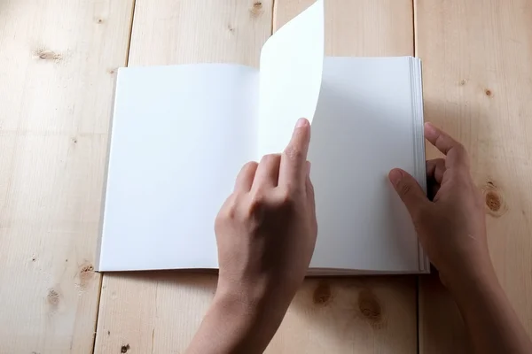 Hands hold book on wood table