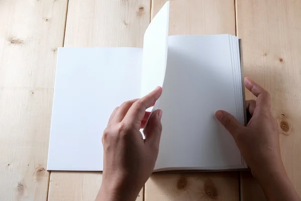 Hands hold book on wood table