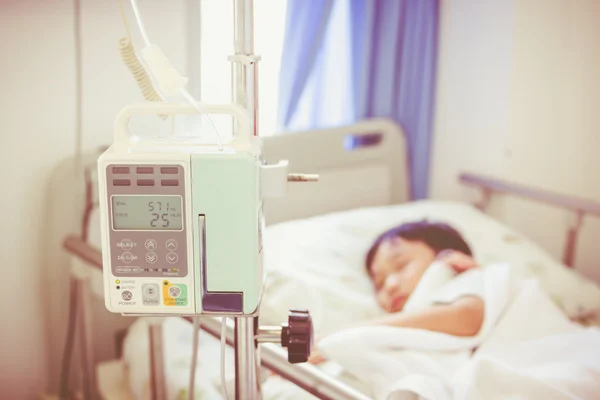 Asian boy lying on sickbed with infusion pump intravenous IV drip