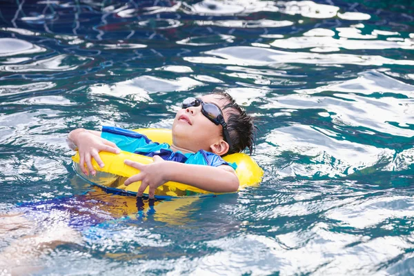 Funny asian boy with swim tube in pool. Outdoor.
