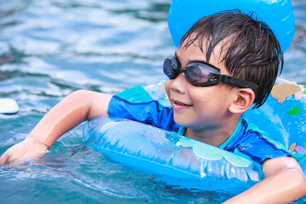 Close up funny asian boy with swim tube in pool. Outdoor.