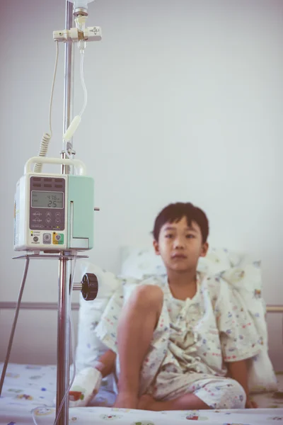 Asian boy sitting on sickbed with infusion pump intravenous IV drip
